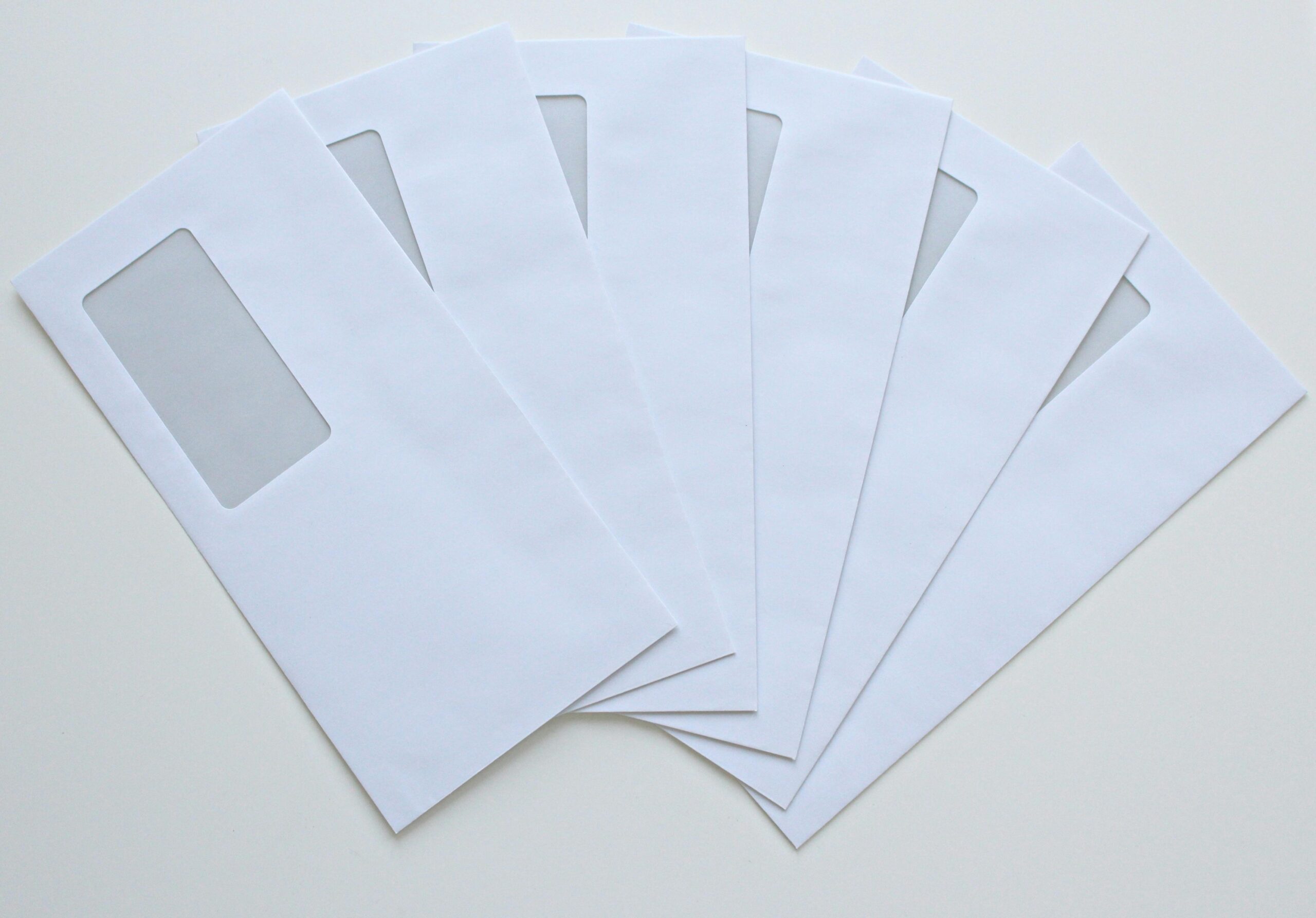 A set of white window envelopes fanned out on a flat surface, ready for mailing or office use.